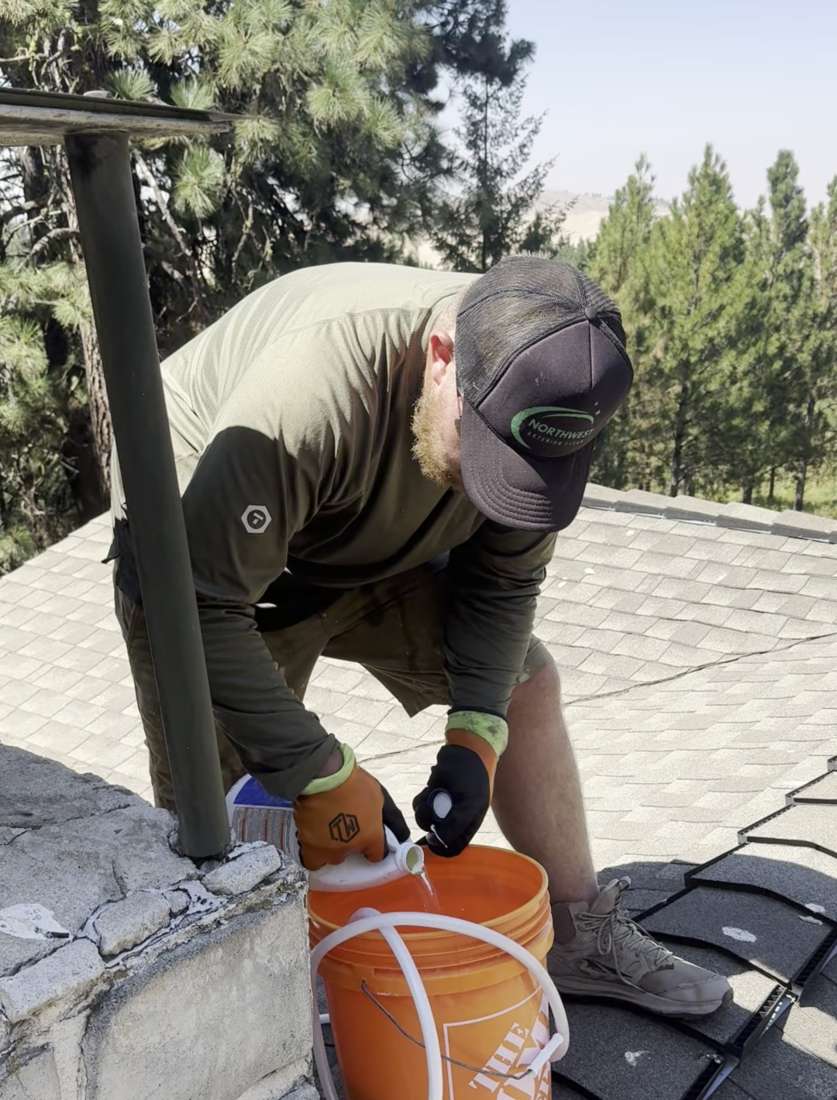 Joe Bertram, owner of Northwest Exterior Clean, treating a roof for moss
